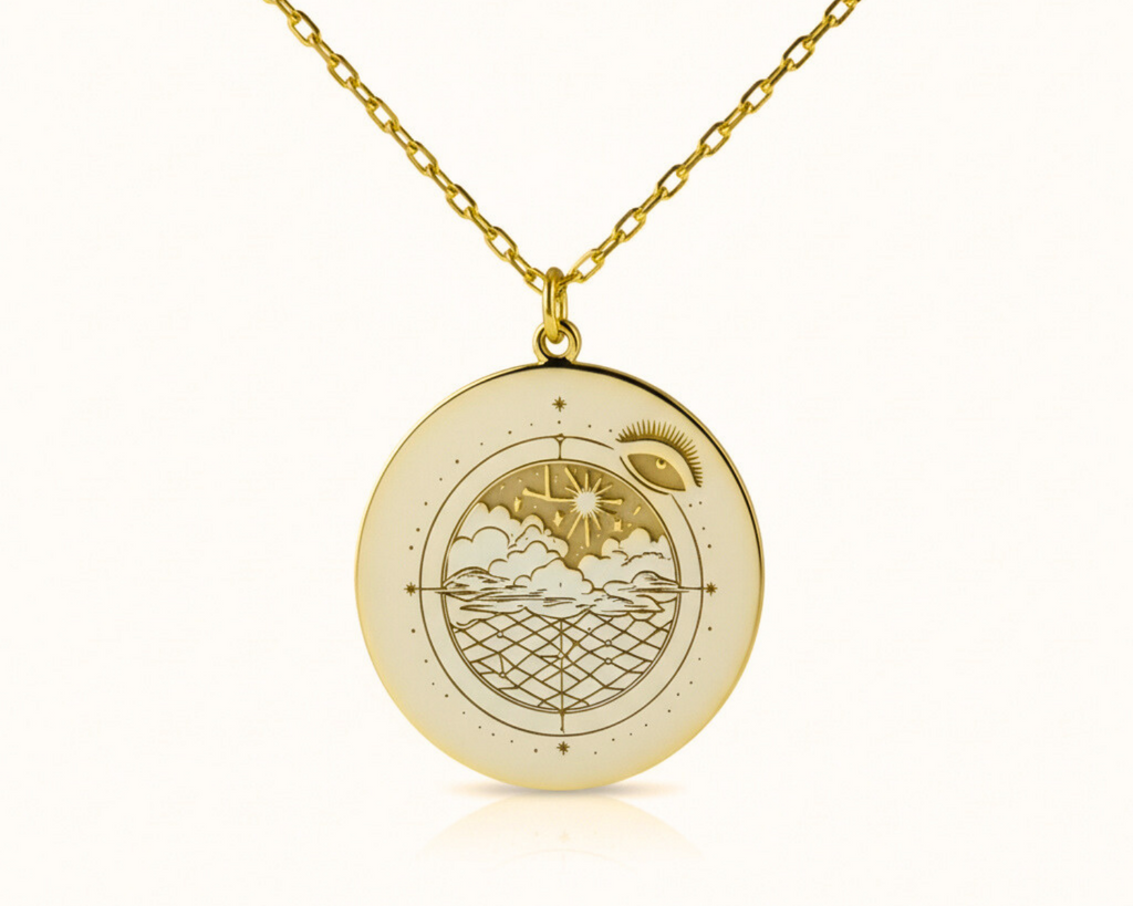 Gold necklace with a round pendant featuring an engraved design on a white background